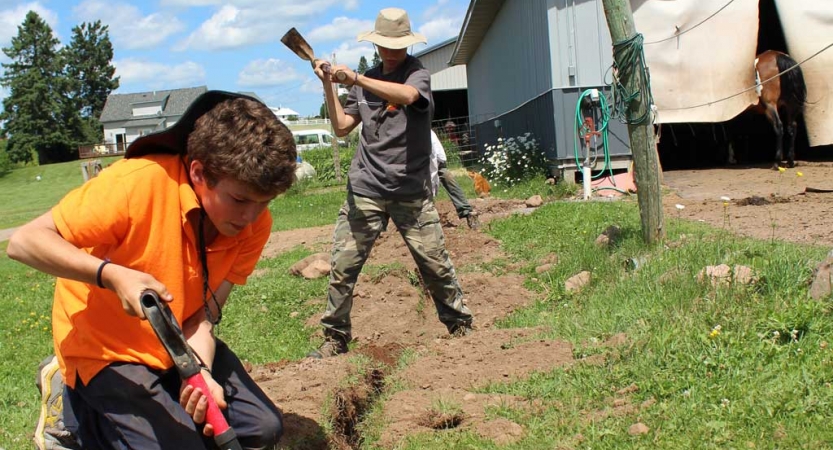 Young people use gardening tools during a service day with Outward Bound. 